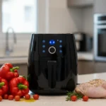 Air fryer preta em bancada de cozinha com legumes e frango